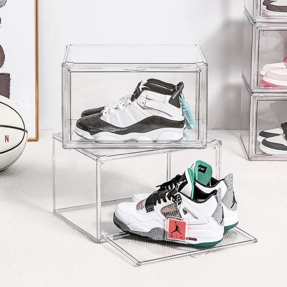 Two clear shoe boxes displaying sneakers in a modern bedroom setting