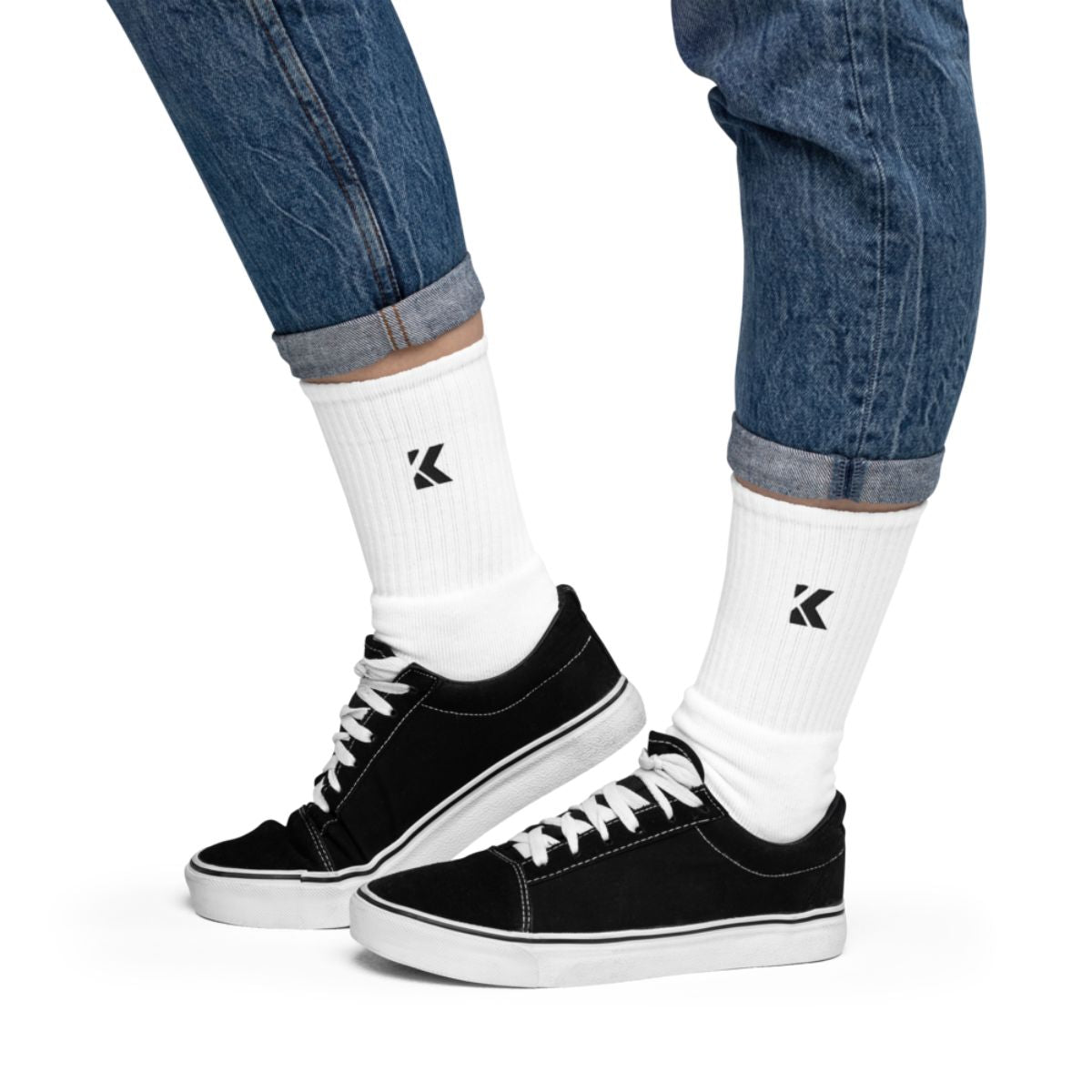 Black sneakers with white laces worn with white socks.