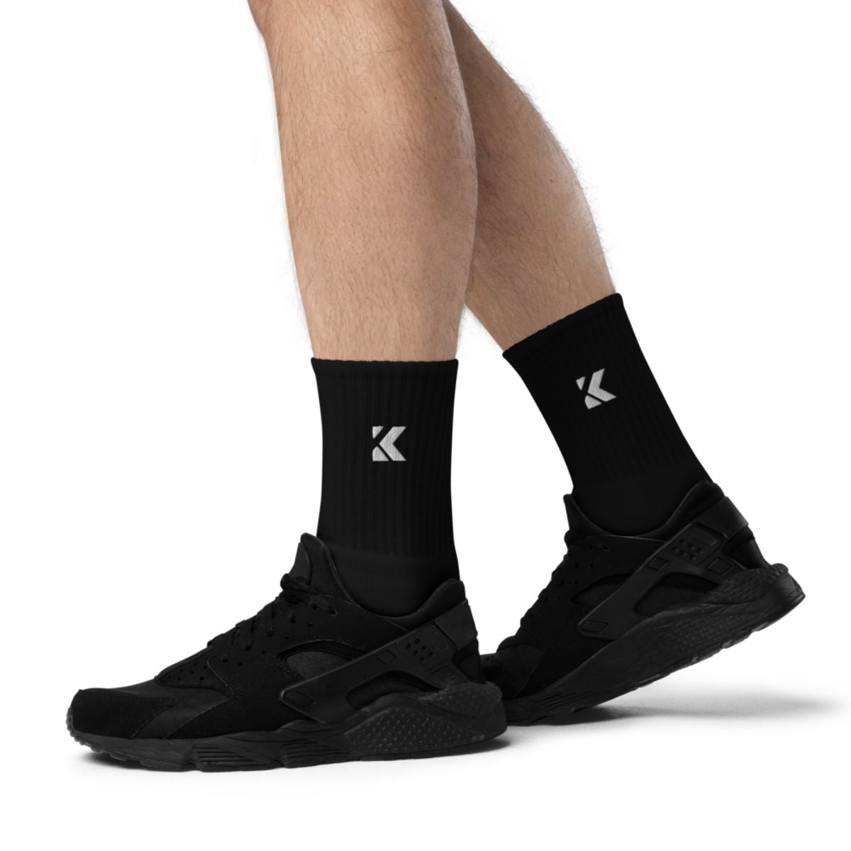Black socks worn with black sneakers on a white background