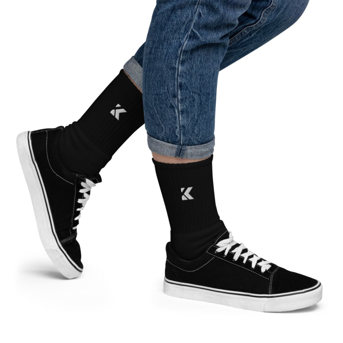 A person wearing black sneakers and socks with jeans.